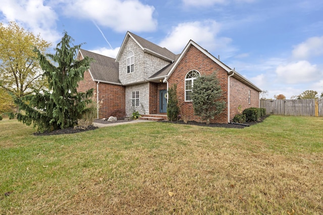 traditional-style house featuring brick siding, a front yard, and fence