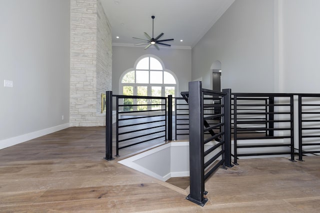 interior space with lofted ceiling, ornamental molding, a ceiling fan, wood finished floors, and baseboards