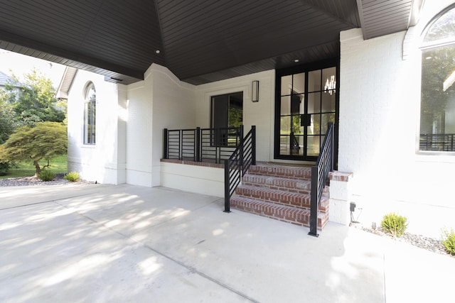 entrance to property featuring covered porch and brick siding