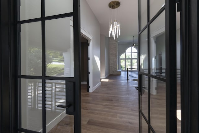 foyer entrance with baseboards, a high ceiling, wood finished floors, and an inviting chandelier