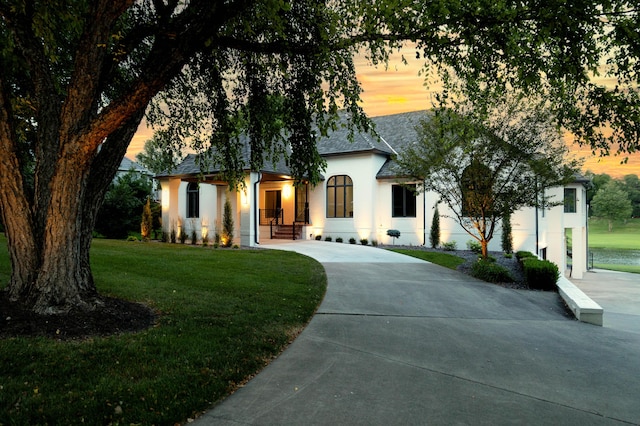 view of front facade with a shingled roof, a front lawn, and stucco siding