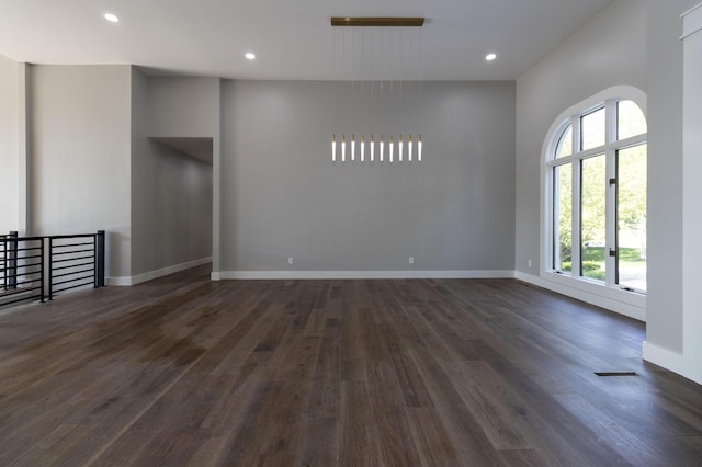 unfurnished room with baseboards, dark wood-type flooring, visible vents, and recessed lighting