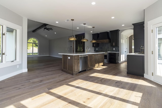 kitchen featuring arched walkways, stainless steel appliances, premium range hood, open floor plan, and light countertops