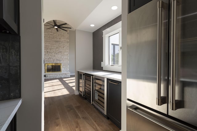 kitchen featuring a fireplace, dark wood finished floors, high end fridge, light countertops, and beverage cooler