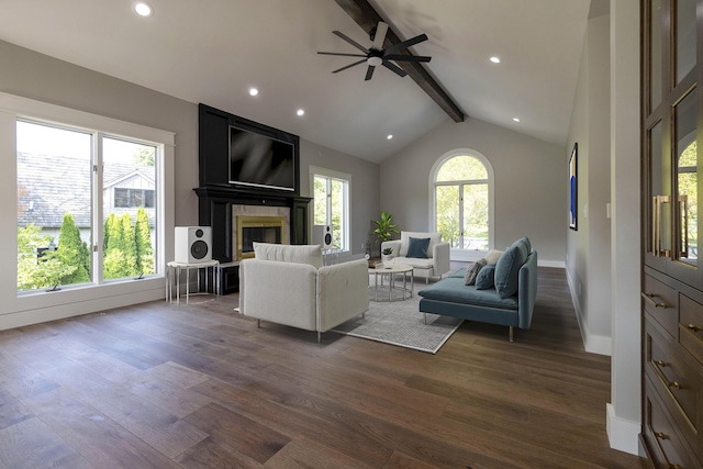 living area featuring a large fireplace, vaulted ceiling with beams, dark wood finished floors, and a healthy amount of sunlight