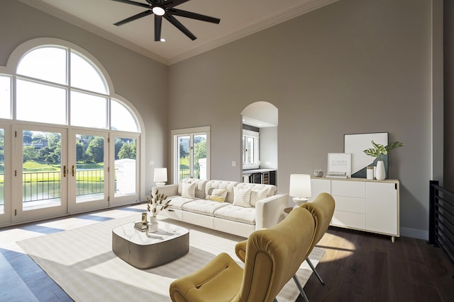 living room featuring dark wood-style floors, arched walkways, a high ceiling, ornamental molding, and baseboards