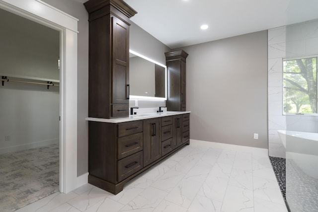 full bath with a freestanding bath, marble finish floor, vanity, and recessed lighting