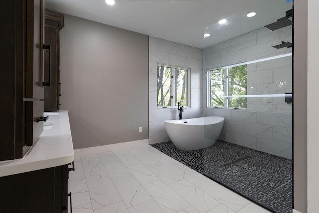 full bathroom featuring a soaking tub, marble finish floor, vanity, a walk in shower, and recessed lighting