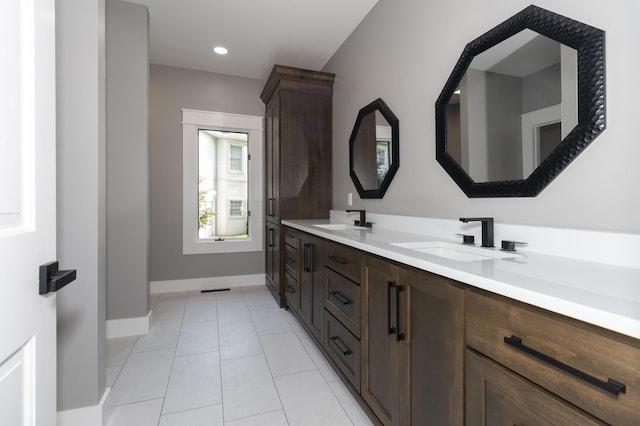 bathroom featuring double vanity, tile patterned flooring, baseboards, and a sink