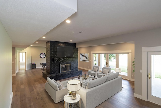 living area with a brick fireplace, recessed lighting, wood finished floors, and french doors