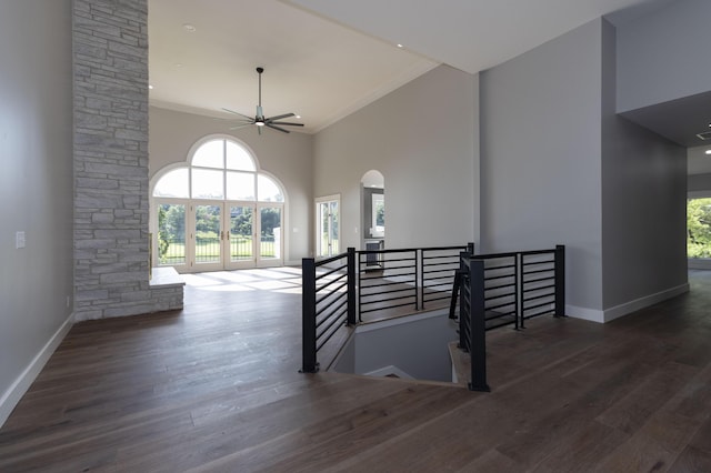 interior space with a healthy amount of sunlight, ceiling fan, a towering ceiling, and wood finished floors