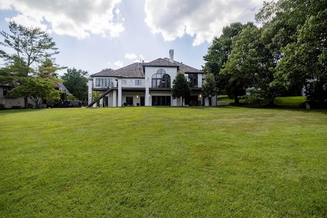 exterior space with a balcony, a front lawn, and stucco siding