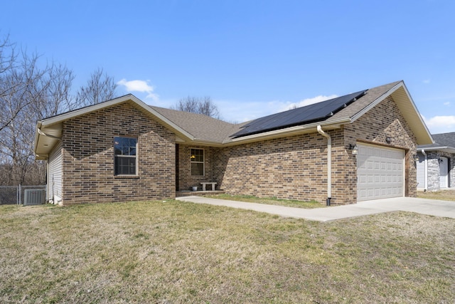 ranch-style house with brick siding, an attached garage, roof mounted solar panels, and a front yard