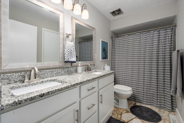 full bath featuring toilet, double vanity, visible vents, and a sink