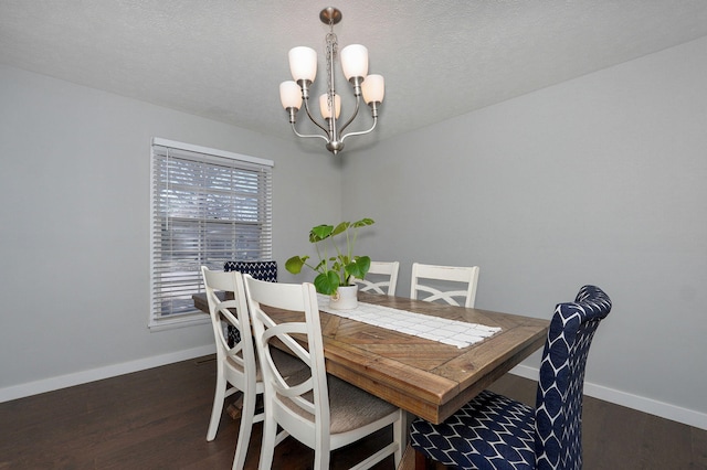 dining area with a chandelier, a textured ceiling, baseboards, and wood finished floors