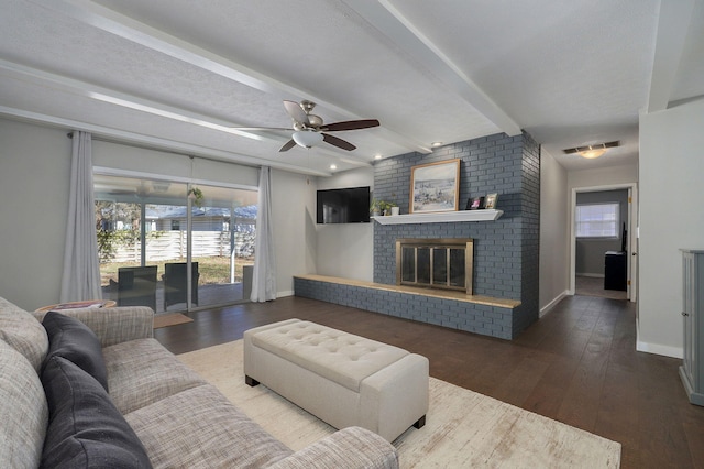 living area with beam ceiling, a fireplace, baseboards, and wood finished floors