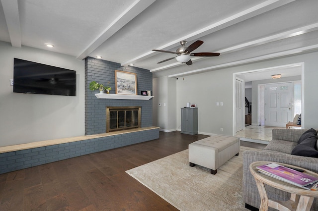 living area featuring a brick fireplace, beam ceiling, baseboards, and wood finished floors