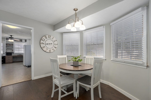 dining room featuring dark wood-style floors, a textured ceiling, baseboards, and ceiling fan with notable chandelier