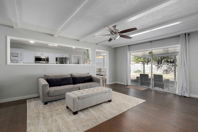 living area with a textured ceiling, ceiling fan, baseboards, beamed ceiling, and dark wood finished floors