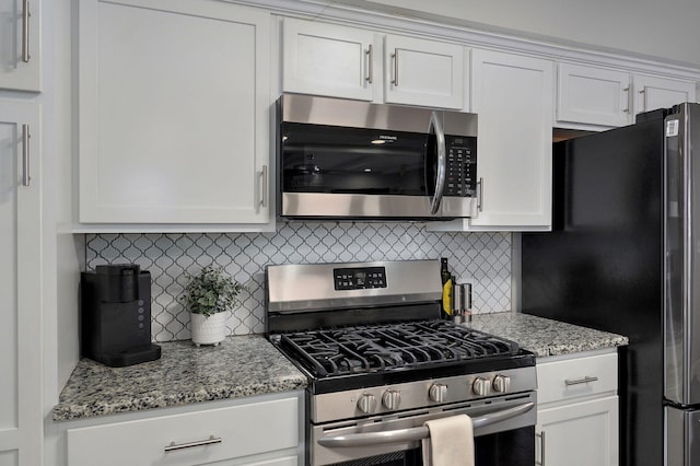 kitchen featuring appliances with stainless steel finishes, white cabinetry, and light stone countertops