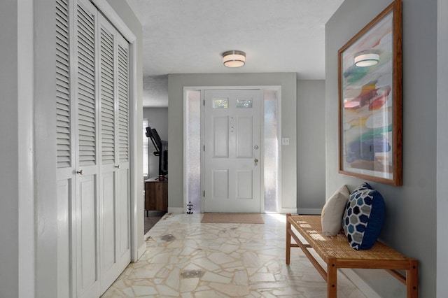 entryway featuring marble finish floor, a textured ceiling, and baseboards