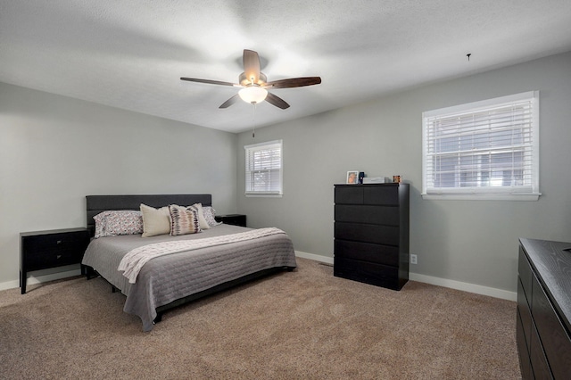 bedroom with a ceiling fan, light colored carpet, a textured ceiling, and baseboards