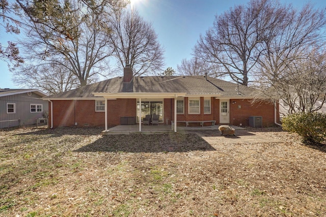 back of house with brick siding, a patio, a chimney, and central AC unit