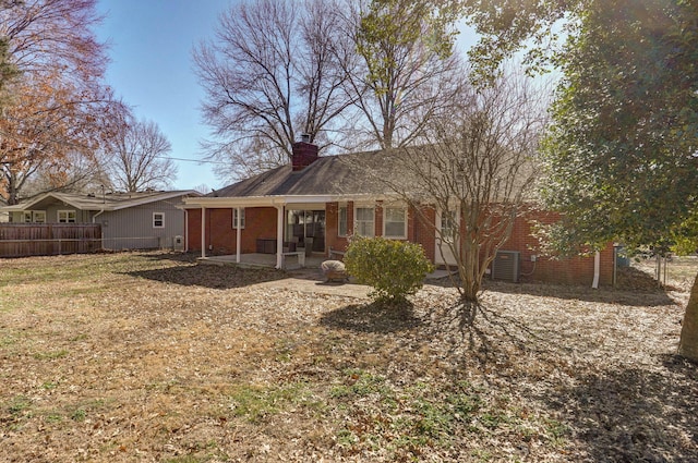 rear view of property featuring a patio area, a chimney, fence, and brick siding