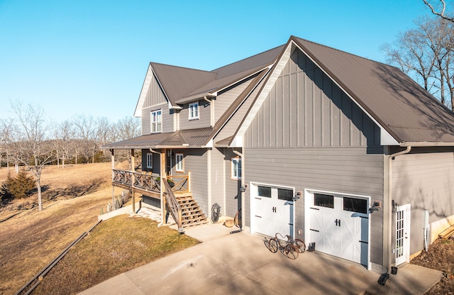 view of front facade with concrete driveway, stairway, board and batten siding, metal roof, and a garage