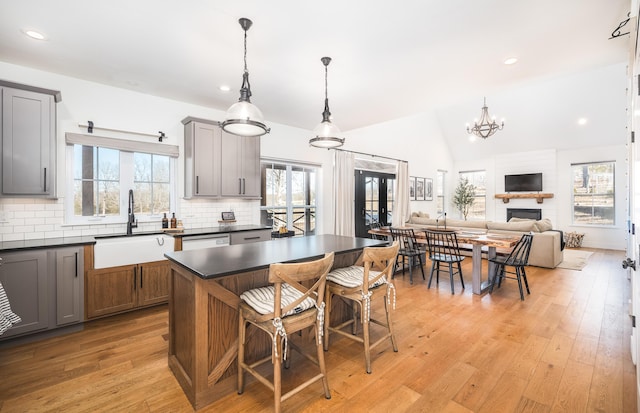 kitchen with dark countertops, gray cabinets, light wood-style floors, a healthy amount of sunlight, and a sink