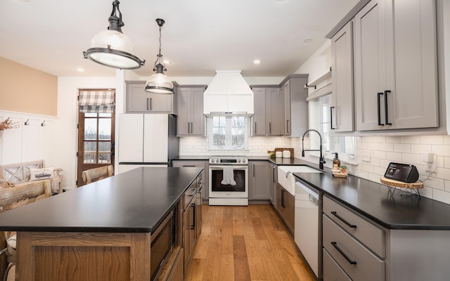 kitchen with stainless steel appliances, dark countertops, a sink, and gray cabinetry