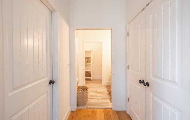 hallway with light wood-type flooring and baseboards