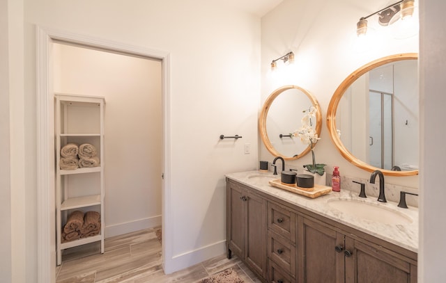 full bathroom with double vanity, wood finished floors, a sink, and baseboards