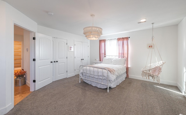 bedroom with carpet floors, baseboards, a chandelier, and multiple closets