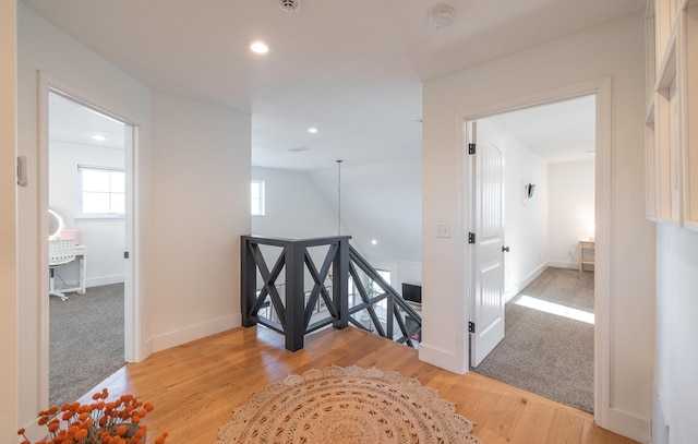 hall featuring light wood finished floors, plenty of natural light, an upstairs landing, and baseboards