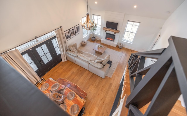 living area with a large fireplace, baseboards, wood finished floors, a notable chandelier, and recessed lighting