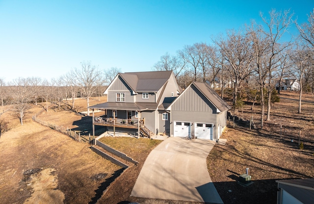 view of front facade with covered porch, a garage, fence, concrete driveway, and board and batten siding