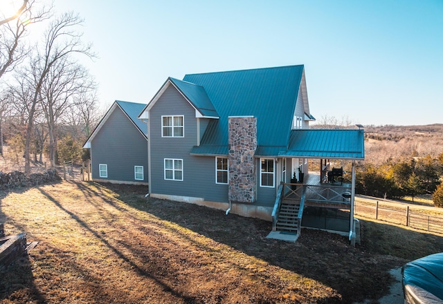 back of property with a standing seam roof, metal roof, a lawn, and fence