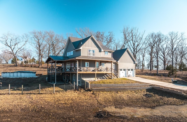 exterior space with stairway, an attached garage, board and batten siding, fence, and driveway