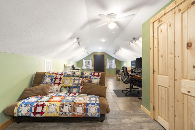 bedroom with vaulted ceiling, ceiling fan, a textured ceiling, and baseboards