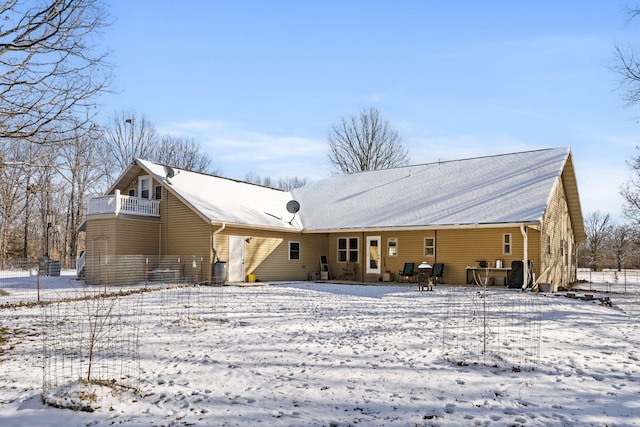 snow covered rear of property with a balcony