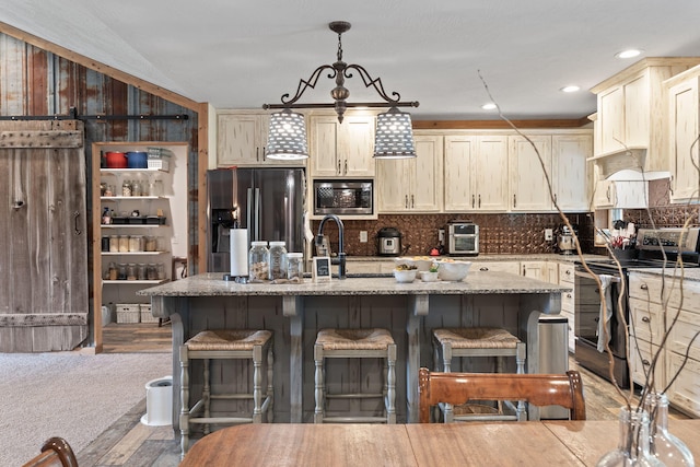 kitchen featuring a kitchen island with sink, tasteful backsplash, a kitchen bar, and stainless steel appliances