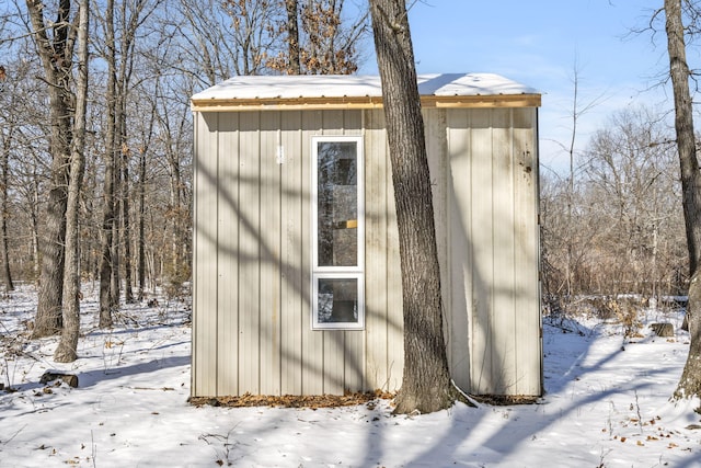 snow covered structure featuring an outbuilding and a shed