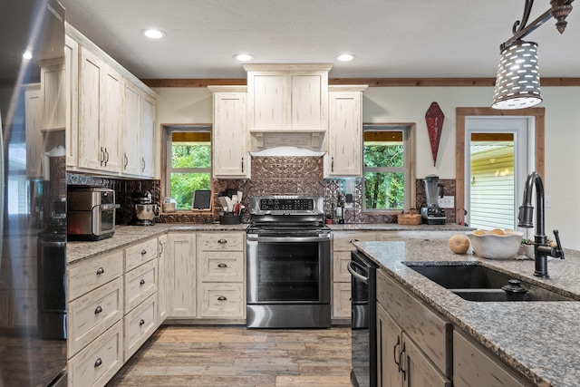 kitchen featuring a sink, light wood-style floors, electric stove, freestanding refrigerator, and decorative backsplash