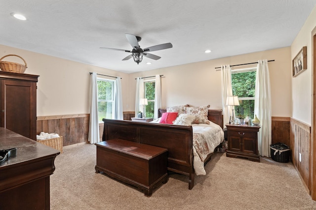 bedroom with a wainscoted wall, wooden walls, and multiple windows