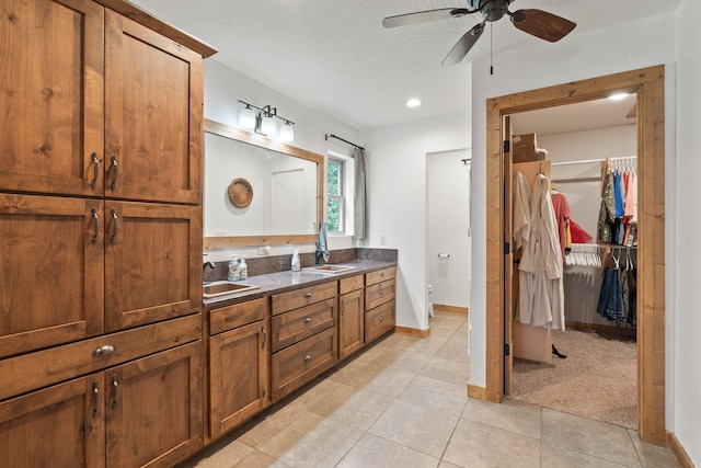 full bath with double vanity, a spacious closet, baseboards, and a sink