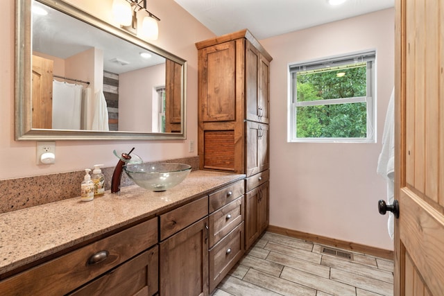 bathroom with wood tiled floor, visible vents, baseboards, and vanity