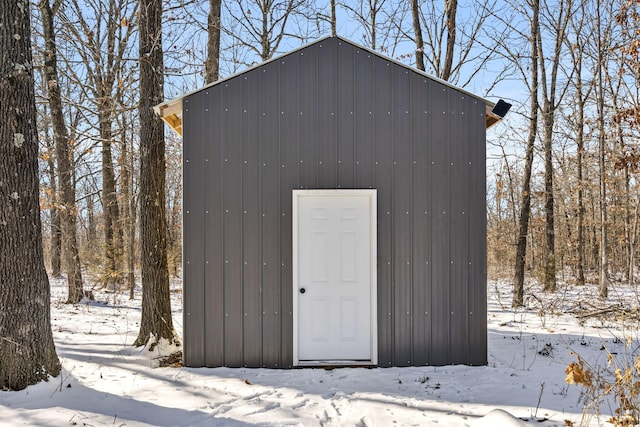 snow covered structure with an outdoor structure and a storage shed