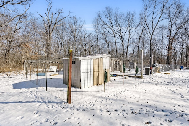 yard layered in snow featuring a storage shed, an outbuilding, and fence