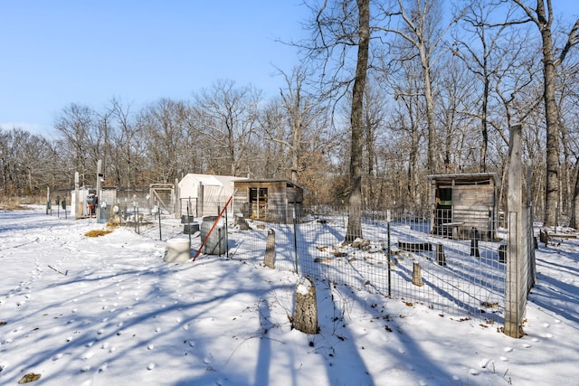 yard covered in snow with an outbuilding and fence